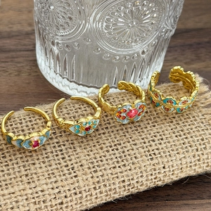 Dettaglio ravvicinato di quattro anelli smaltati vintage con motivi cloisonné colorati