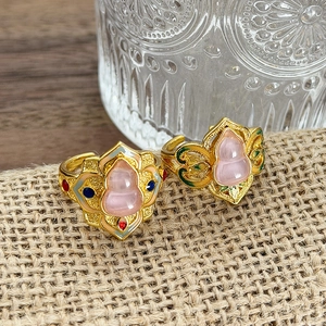 Dettaglio di anelli dorati vintage con pietra a forma di zucca rosa e smalto colorato