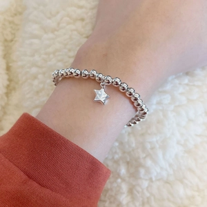 Detailaufnahme eines Perlenarmbands mit Sternanhänger und eingraviertem Smiley-Gesicht