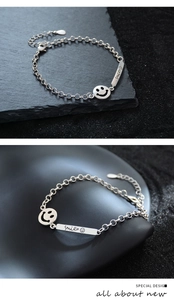 Detailed macro view of silver smile pendant bracelet on a textured black stone surface