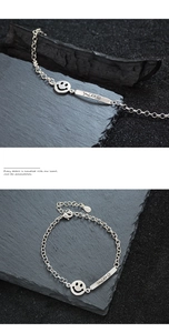 Macro detail of silver smile bracelet featuring engraved Smile bar and round pendant