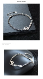 Detail of silver link bracelet featuring hollow smile charm and engraved smile tag