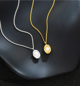 Close-up of gold and silver peanut pendant necklaces with pearls on a dark display stand