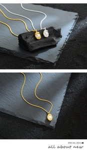 Detailed close-up of gold and silver peanut-style pearl pendants on black texture