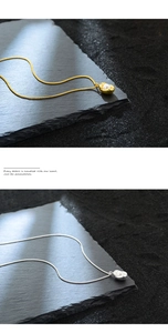 Detail of peanut shell pearl pendant necklaces in gold and silver finish on textured stone