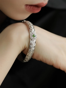 Détail d'un bracelet tissé en argent avec pierre précieuse vert émeraude et zircons
