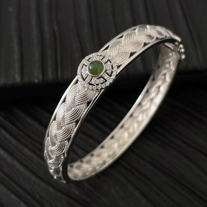 Vue macro d'un bracelet en argent tressé orné d'une pierre verte et de zircons fins