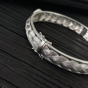 Détail macro du bracelet argenté tressé montrant la texture délicate et le fermoir latéral