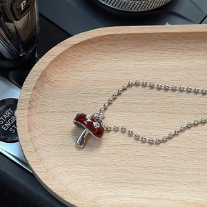Vue macro détaillée d'un pendentif champignon en émail sur un collier à chaîne à billes