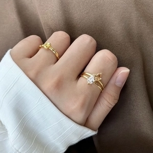 Nahaufnahme von goldenen Lavatextur-Ringen mit Zirkon-Tropfen an der Hand