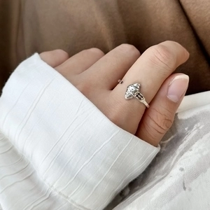 Detailaufnahme eines silbernen Rings im Croissant-Design mit kleiner Gabel