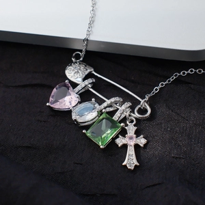 Collier épingle de sûreté argenté avec breloques cœur et croix colorées sur fond sombre
