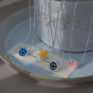 Vue détaillée des pendentifs smileys en émail coloré sur chaînes argentées sur une tasse