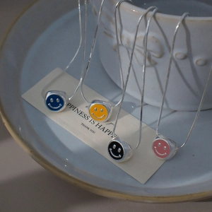 Détail de pendentifs cubes souriants en émail coloré sur un bol en céramique blanche