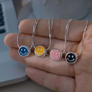 Gros plan de pendentifs smileys colorés en émail sur chaînes serpent argentées