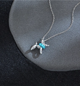 Detailed view of silver balloon dog necklace with bright turquoise beads on dark base