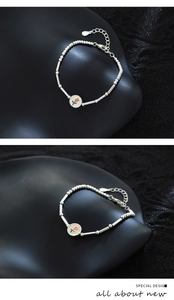 Gros plan d'un bracelet en perles argentées avec pendentif fleur sur fond noir