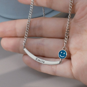 Schicke Silberhalskette mit Smile Gravur und blauem Emaille Anhänger in der Hand