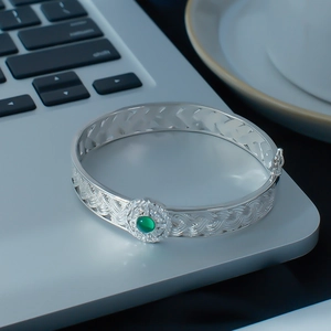 Detail of silver lace woven bracelet with green gemstone and secure side safety clasp