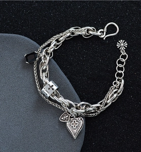 Close-up of vintage silver layered chain bracelet with cross heart and black zircon pendants