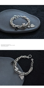 Detail of vintage silver layering bracelet with cross heart charm and black gemstone