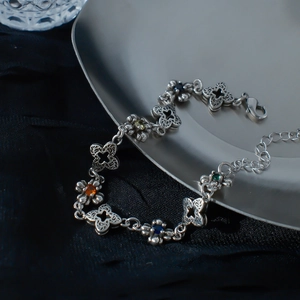 Bracelet trèfle vintage en argent avec zircons colorés sur fond de satin noir