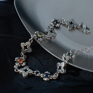 Bracelet trèfle exquis en ton argent avec zircons colorés sur un fond en soie de luxe