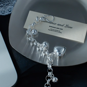 Makroaufnahme des silbernen Gliederarmbands mit polierten Kugeln und Herzanhänger