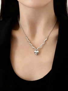 Collana con ciondolo a cuore argento con catena ondulata su modella con blazer nero