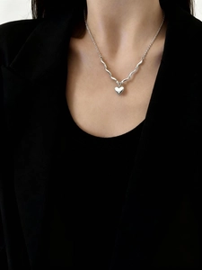 Dettaglio di una collana con ciondolo a cuore in argento indossata con un blazer nero