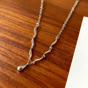 Collana d'argento elegante con maglie ondulate e un ciondolo lucido a goccia d'acqua