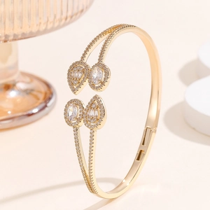 Detailed view of a gold double-layer open bangle set with teardrop and oval cubic zirconia