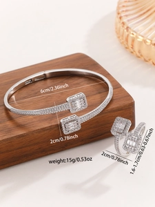 Detailed close-up of silver zircon bangle and ring set on a wooden display stand