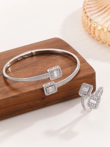 Detailed view of silver luxury jewelry set with emerald cut zircons on a wooden display