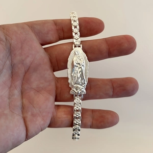 Silver metal bracelet featuring detailed Virgin of Guadalupe relief and floral chain links