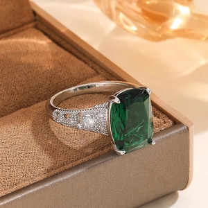 Elegant emerald cut green stone ring with pavé diamonds on a silver band shown in a gift box