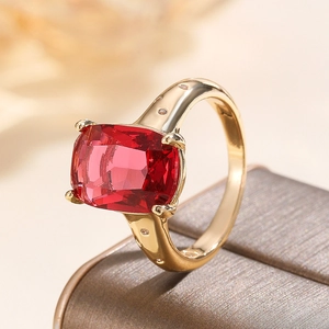 Elegant gold ring featuring a cushion-cut red gemstone and delicate white side stones
