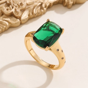 Macro shot of rectangular green emerald ring with four-claw setting and gold finish