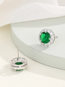 Dettaglio di orecchini a perno con zircone verde e montatura argento su base elegante