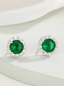 Dettaglio di orecchini a lobo con zircone verde smeraldo e halo di pietre bianche in argento