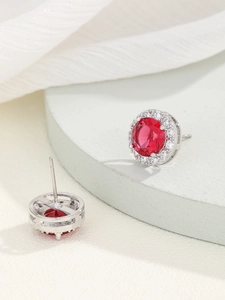 Dettaglio di orecchini a lobo in zircone rosso con design halo e dettagli sul retro