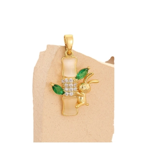 Bamboo and rabbit gold pendant with cat eye stones and green gems on a stone stand