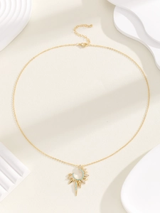 Detail of gold tarot sun necklace with turquoise inlay and sparkling crystals
