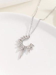 Detail of silver sun flower and crescent moon necklace with colorful stones on ceramic tray