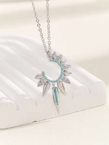 Macro shot of silver crescent pendant with turquoise beads and zircon on white stand