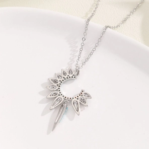 Silver tarot sun and moon necklace with turquoise inlay on a white ceramic plate