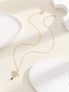 Detalle de collar de flor de lis dorada con circón rojo y colgante de cristales pavé