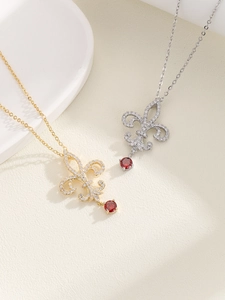 Detalle de los collares de flor de lis en oro y plata con circón rojo y pavé de piedras