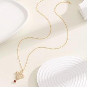 Elegante collar de flor de lis dorada con circón rojo y pavé de cristales en bandeja blanca