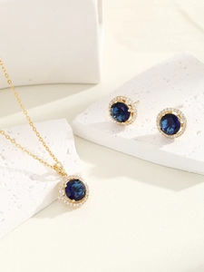 Detailed view of luxury jewelry set with blue sapphire stones and zircon halo on white stone